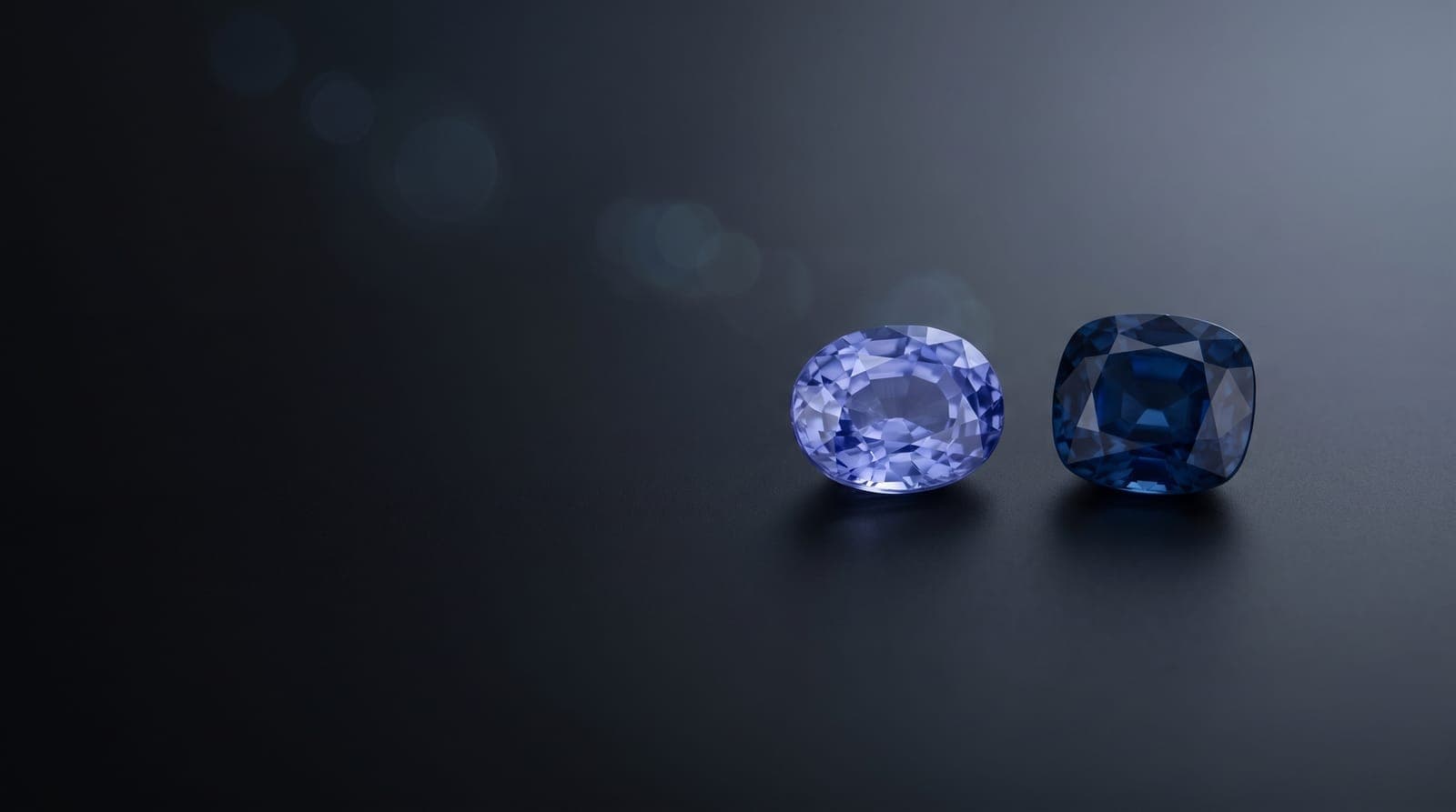 Loose blue sapphires beside a precision measuring gauge on a cream backdrop