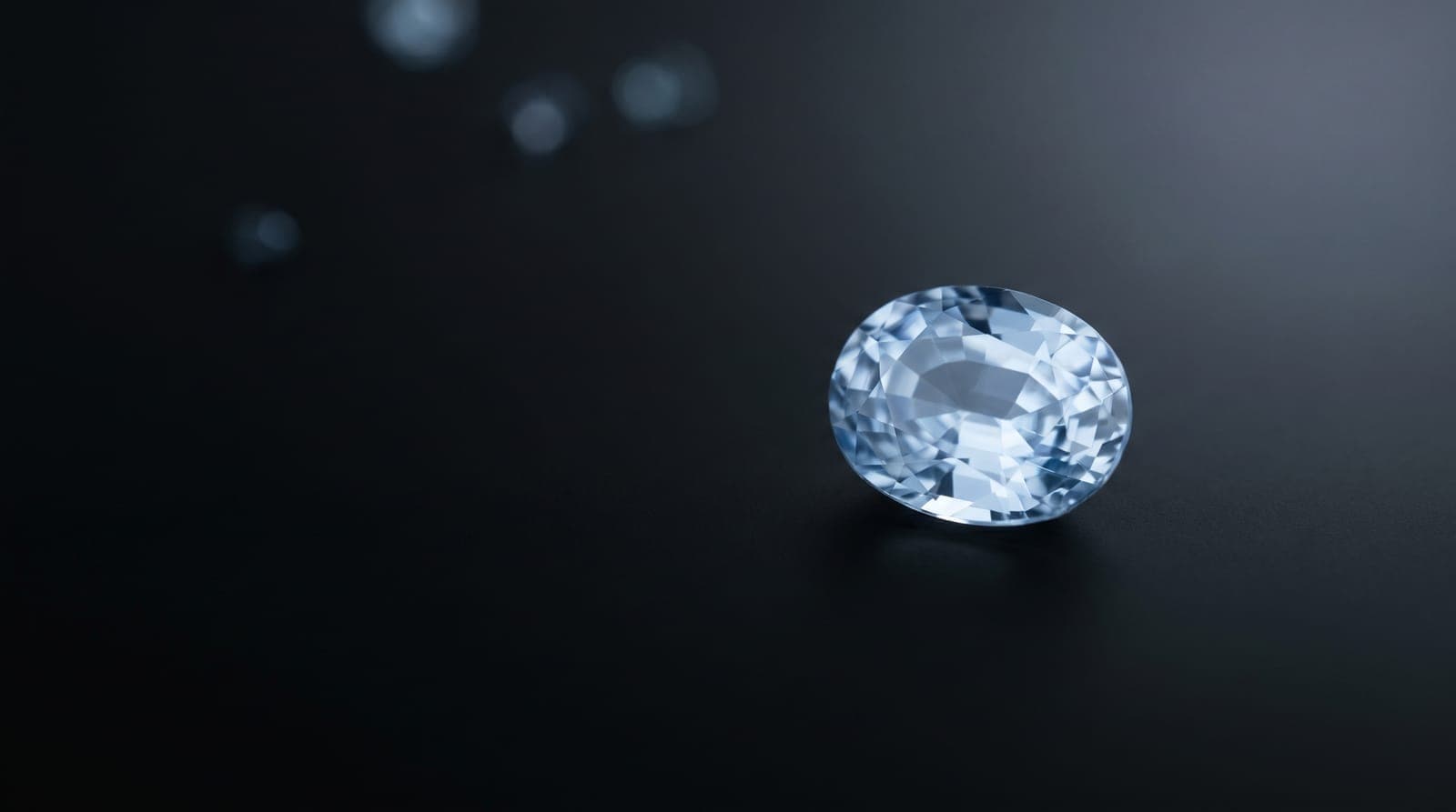 Three gemstone lab reports laid out beside certified colored gemstones